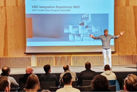 Ein Mann präsentiert auf der Bühne eine PowerPoint